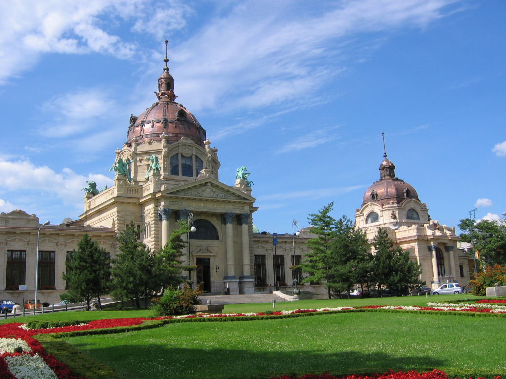 Historic exterior of the Széchenyi thermal baths in Budapest beside green lawns