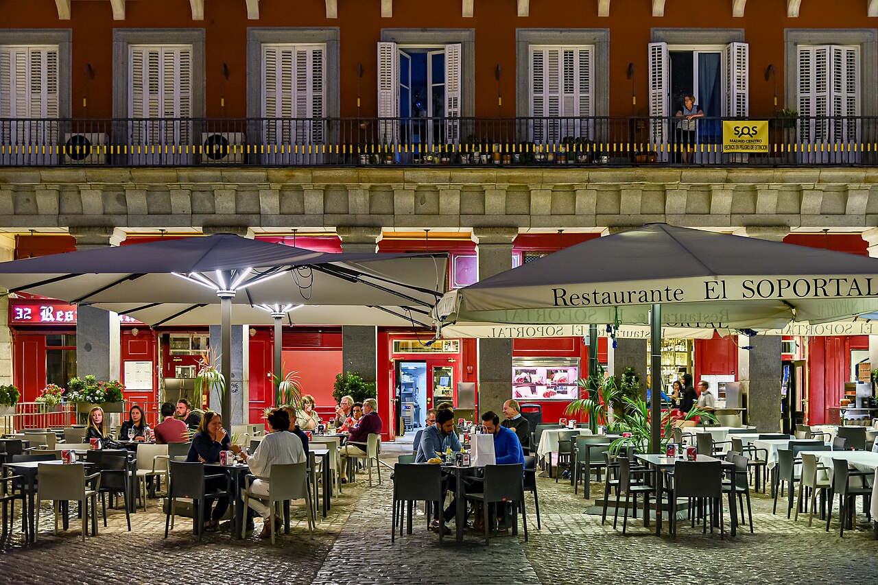 Evening restaurant terraces beneath the arcades of Madrid’s Plaza Mayor