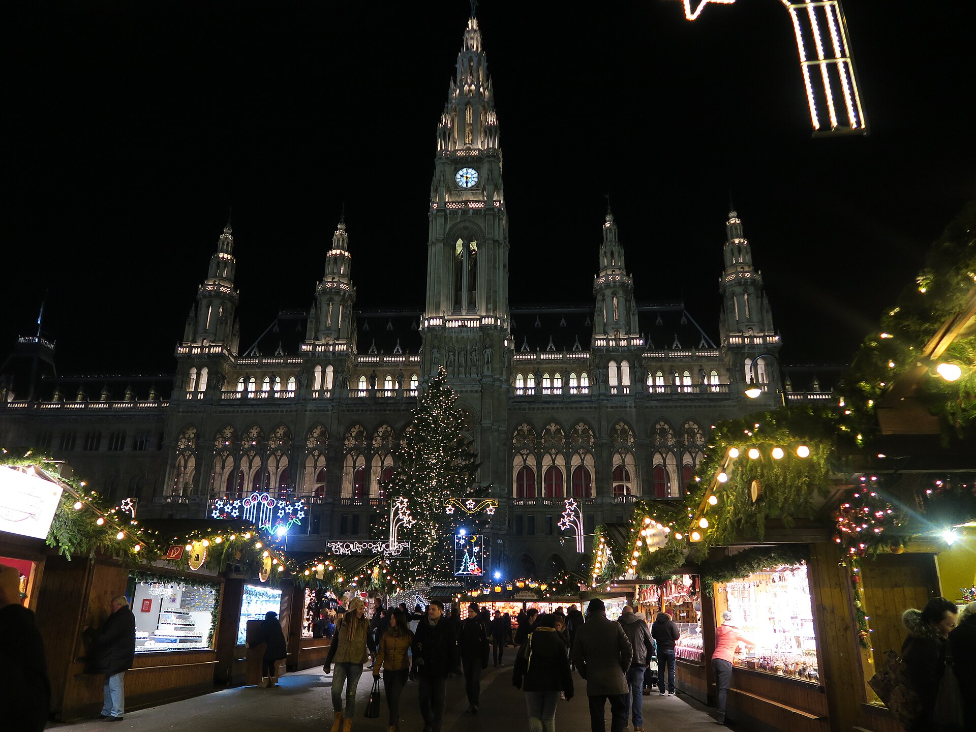 Vienna Rathaus illuminated behind the Christmas market and tree